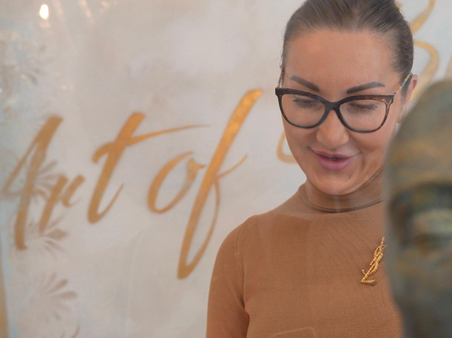 Magdalena Peters lächelt vor dem Schriftzug Art of Beauty in ihrer Praxis
