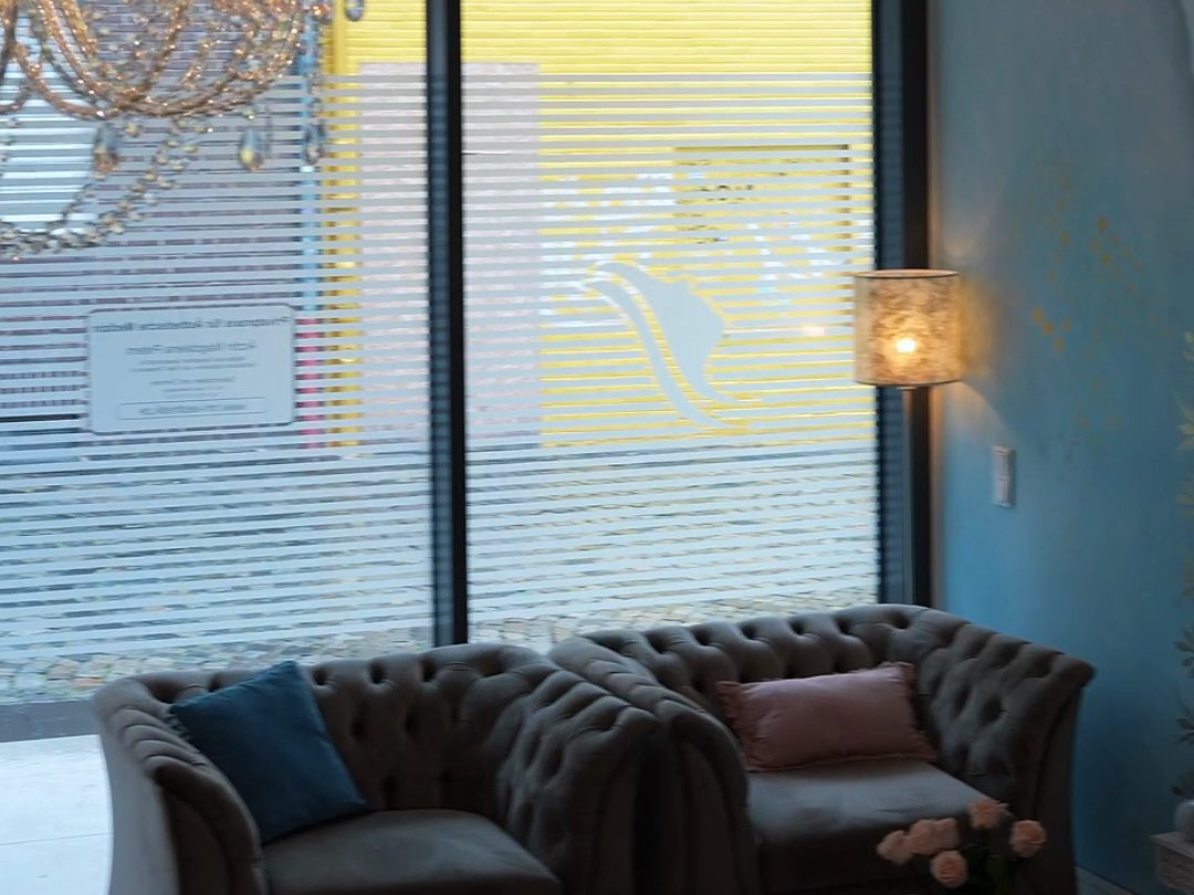Lounge mit Samtsofas und großem Fenster im Eingangsbereich der Praxis